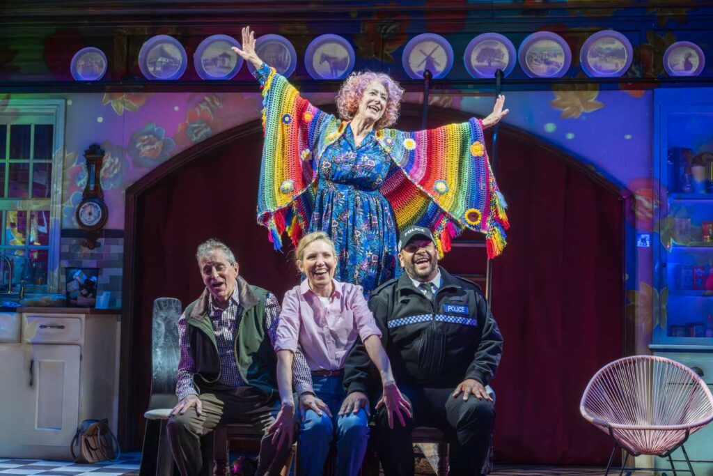 Dame Maureen Lipman as Allegra stands above John Middleton as Ronen, Elizabeth Bower as Anna and Bailey Patrick as Officer Rogers during a colourful musical number.