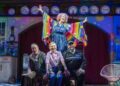 Dame Maureen Lipman as Allegra stands above John Middleton as Ronen, Elizabeth Bower as Anna and Bailey Patrick as Officer Rogers during a colourful musical number.