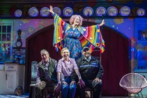 Dame Maureen Lipman as Allegra stands above John Middleton as Ronen, Elizabeth Bower as Anna and Bailey Patrick as Officer Rogers during a colourful musical number.